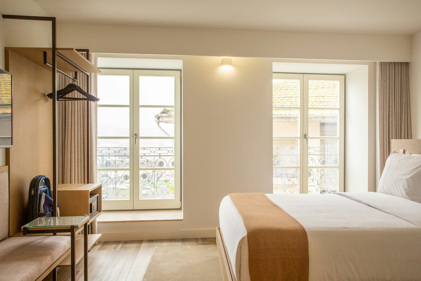 Hotel room with a made bed and urban view.