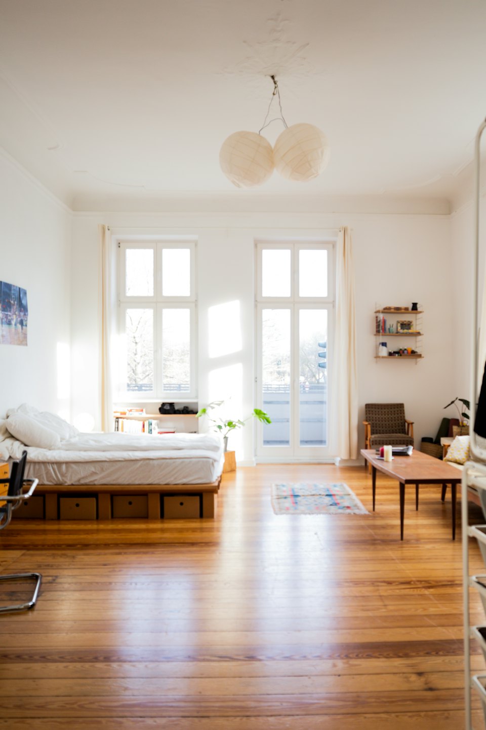 Modern bedroom and living area with large windows and wooden floors.