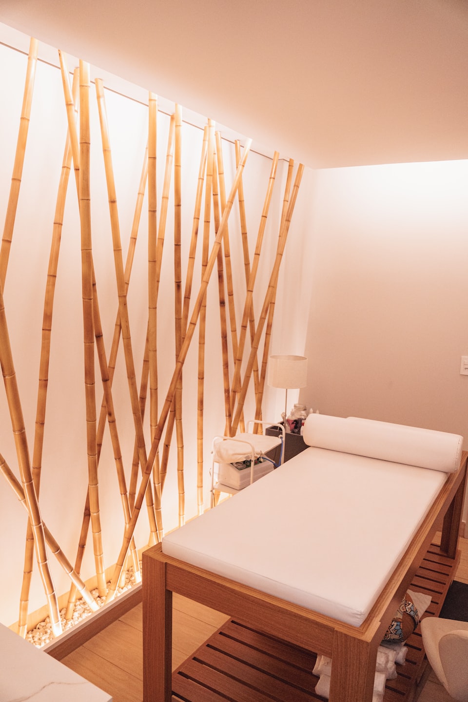 Empty spa room with bamboo wall and massage table.