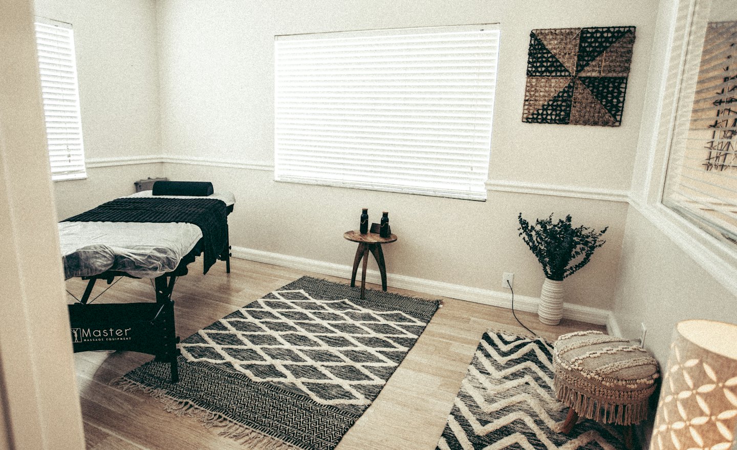 Massage room with a black table on a patterned rug.